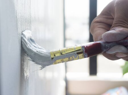 Man painting the house wall with brush wooden.
