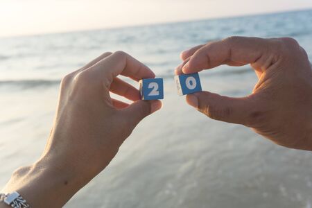 Man and women holds a Number two and zero in hands, sunset, sea background.の写真素材