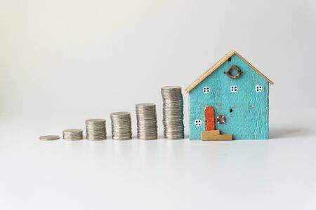Stacked silver coins, stacked in height order with Beautiful small house on white background. Real Estate Business Growth Concept.の写真素材