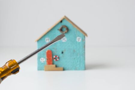 Handheld screwdrivers focus on screwdrivers. Small house as a background, home repair ideas.の写真素材