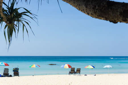 White beach with beach chairs and colorful umbrellas, beautiful sea and blue sky, Phuket, Thailand.