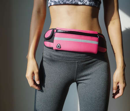 Woman preparing for exercise, wearing a gym clothes and a pink waist bag.の写真素材
