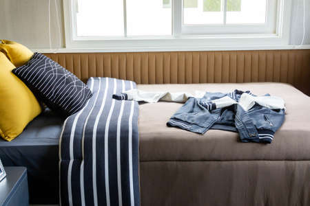 Bed with blue and white striped duvet and 2 yellow pillows and black and white striped pillows, blue...