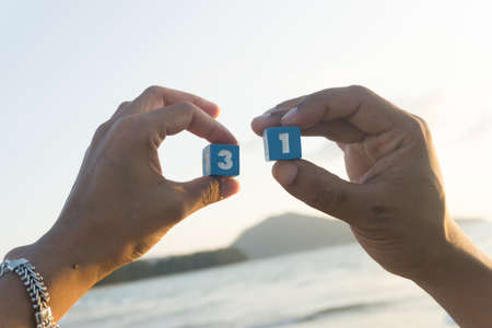 Man and women holds a Number thirty one in hands, sunset, sea background.の写真素材