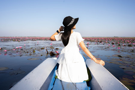 Asian tourist women Take a ride on a blue long-tail boat,amazing red lotus sea, unseen in Thailand, Udon Thani Province Thailand.の写真素材