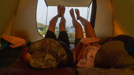 Two Asian tourists put both legs in a tent, enjoying a camping holiday.の写真素材