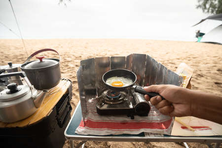 Camping tourists cook fried eggs on a frying pan, Camping on the beach.の写真素材