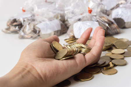 A gold coin in a woman's hand, she is collecting coins to spend on her daily life, losing her job because of the coronavirus.の写真素材