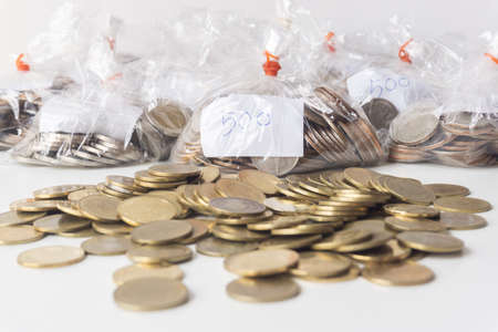 A clear plastic bag with money inside and lots of gold coins on a white background, Saving money, bringing savings to spend during the COVID-19 pandemic.の写真素材