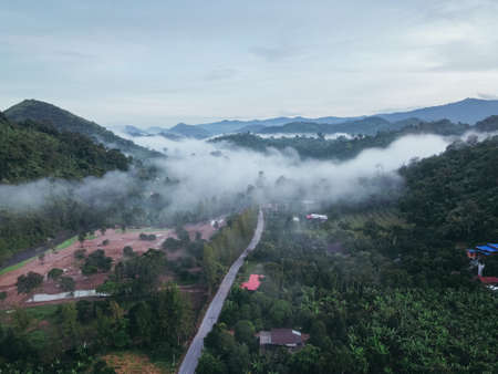Aerial view of countryside in mist, fog moving through mountains, sky in the morning, fog of a scenic road.の写真素材