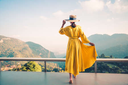 Asian female tourist in yellow dress with beautiful mountain view of nature.の写真素材