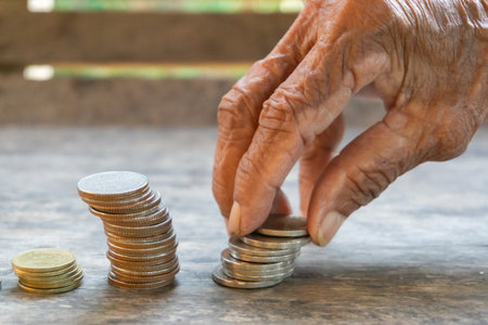 Thai baht in old woman's hand, coins are stacked, money saving idea.の写真素材