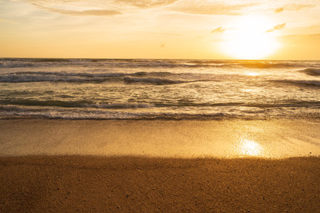 Colorful Orange and golden sunset sky, reflection of sun in the water and sand on beach.の写真素材