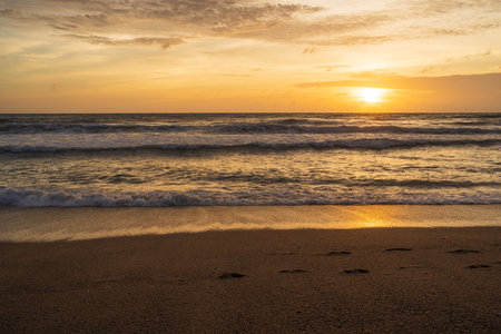Colorful Orange and golden sunset sky, reflection of sun in the water and sand on beach.の写真素材