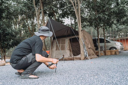 Outdoor tourists are setting up camping tents on rocky ground under trees on vacation.の写真素材