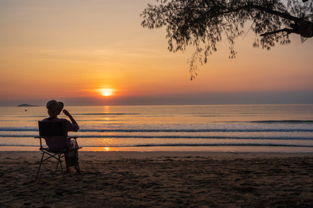 women sit on a chair on the beach with beautiful sea and sunrise sky, 
Outdoor lifestyle concept.の写真素材