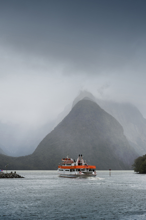 Milford Sound, New Zealand - February 2016: Tourist boat cruises in the fjord of Milford Sound, South island of New Zealand, with Mitre Peak seen in backgroundのeditorial素材