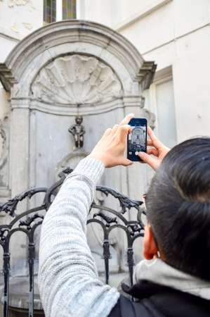 Brussels, Belgium - April 2015: Tourist taking photo of Manneken Pis or Little Man Pee, a landmark small bronze sculpture designed by HiÃ«ronymus Duquesnoy the Elder, located near Grand Place in the city of Brussels, Belgiumのeditorial素材