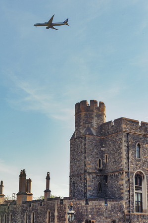 Windsor, UK - April 2018: Group of buildings at The Lower Ward of Windsor Castle, a royal residence at Windsor in county of Berkshire, England, UK, with an airplane flying overのeditorial素材