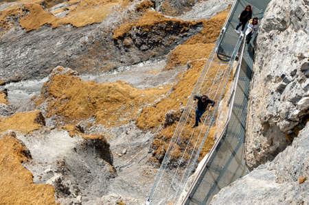 Lauterbrunnen, Switzerland - October 2019: Tourists walking on the Thrill Walk, the cliff pathway down into vertical walls of imposing rock massif located under Birg cableway station at Schilthorn mountain in the Alps, Switzerlandのeditorial素材