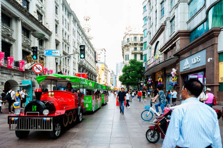 Shanghai, China - September 2019: Tourists riding mini sightseeing train along the walk street on...