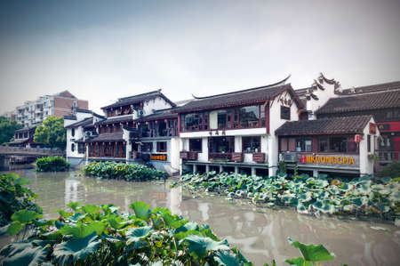 Shanghai, China - September 2019: Traditional Chinese teahouses and buildings along the riverbank of the Puhui River in Qibao Ancient Town, a historic water township of Qibao in the Minhang District of Shanghai, Chinaのeditorial素材