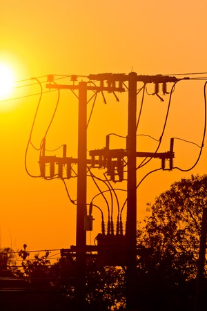 Silhouette of electric pole power lines and wires in sunset sky