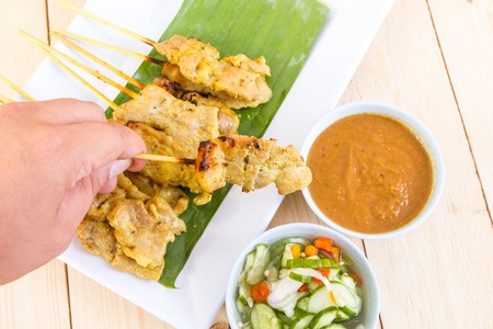 Man hand hold Grilled pork set on wood table , thai food styleの写真素材