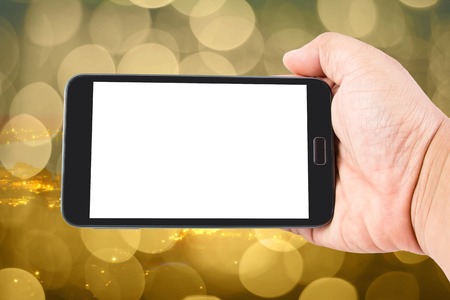 Man hand hold blank touch screen smart phone on abstract blurred bokeh of city night light background.の写真素材