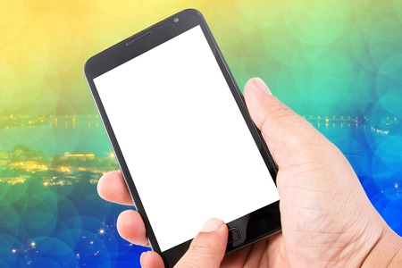 Man hand hold blank touch screen smart phone on abstract blurred bokeh of city night light...