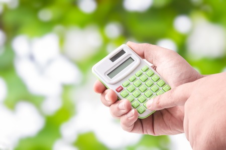Man hand holding with calculator on Green bokeh backgroundの写真素材