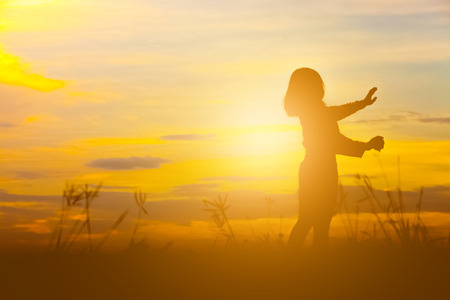 Silhouette of happy young woman over beautiful twilight sunset.の写真素材