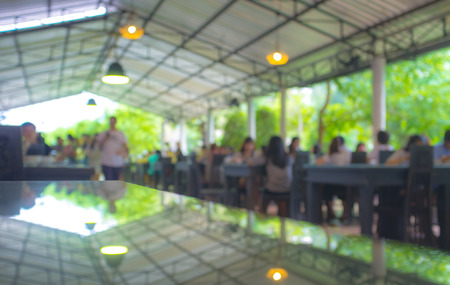 Blurred people eating and light reflector on table