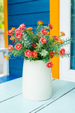 Plastic flowers in pot on blue tableの写真素材