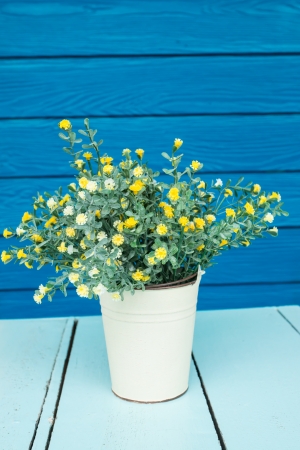 Plastic flowers in pot on blue tableの写真素材