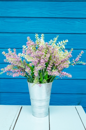 Plastic flowers in pot on blue tableの写真素材