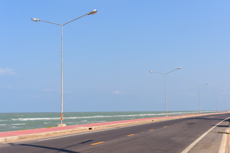 Asphalt road and sea with street lightの写真素材