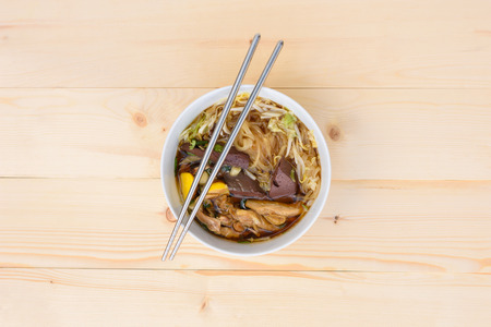 noodle soup with chopsticks in bowl on a wooden table, top view, Thai local foodの写真素材