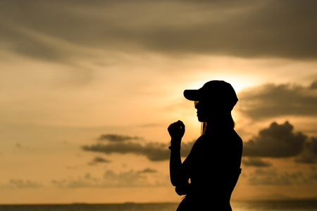 woman wear a sunglasses and cap with sunset silhouetteの写真素材