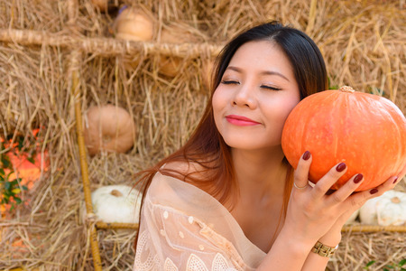 closeup portrait of happy woman and holding a big orange pumpkin in handの写真素材