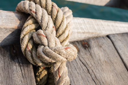 Rope tied up to a knot on a wood bridge