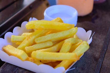 Fresh french fries in a paper container on wood tableの写真素材