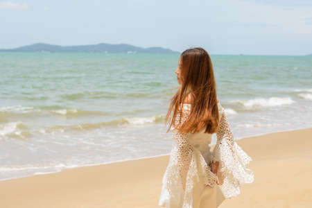 Portrait woman standing on sand sea outdoorの写真素材