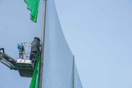 The worker on a construction site installation a net on the craneの写真素材
