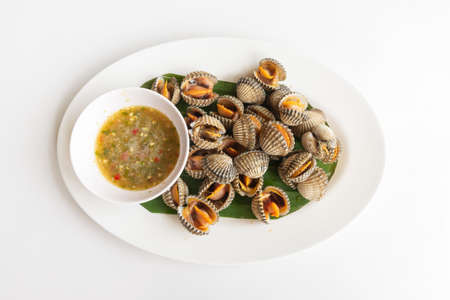 Cockle steamed with seafood sauce on a white table Thai local food, Close-up top view.の写真素材