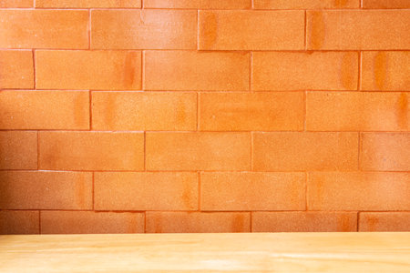 Empty top of wooden table with a brick wall orange background.の写真素材