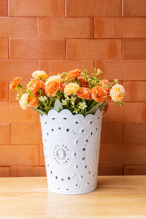 Mockup flower on top of a wooden table with a brick wall orange background.の写真素材