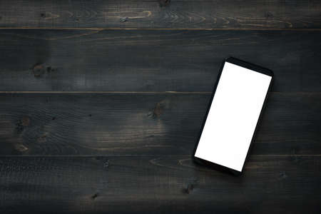 Mockup smartphone blank screen on a wooden table, top view, flat lay, and copy space