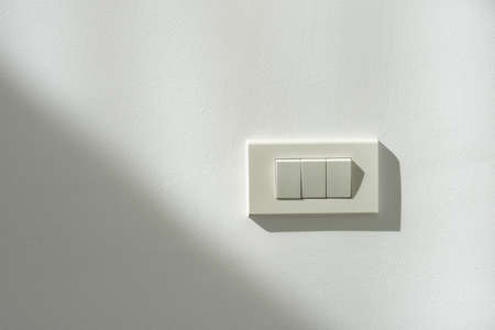 White switch power on a white wall with light and shadow contrast.の写真素材