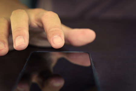 Close up of hand finger pointing on a device mobile phone.の写真素材